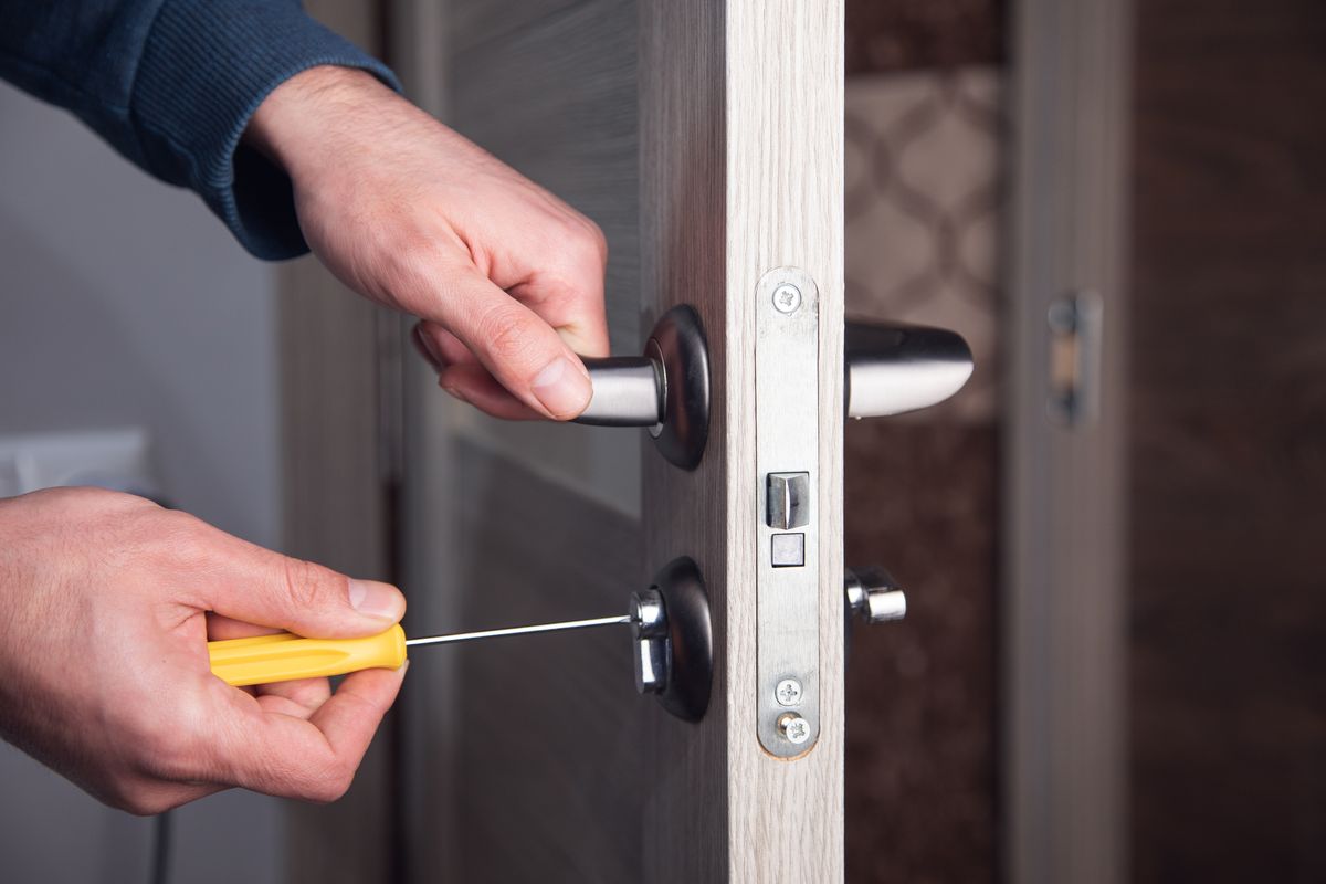Handwerker repariert mit dem Schraubendreher ein Türschloss, sorgfältige Arbeit von Butzbach Facility & Service