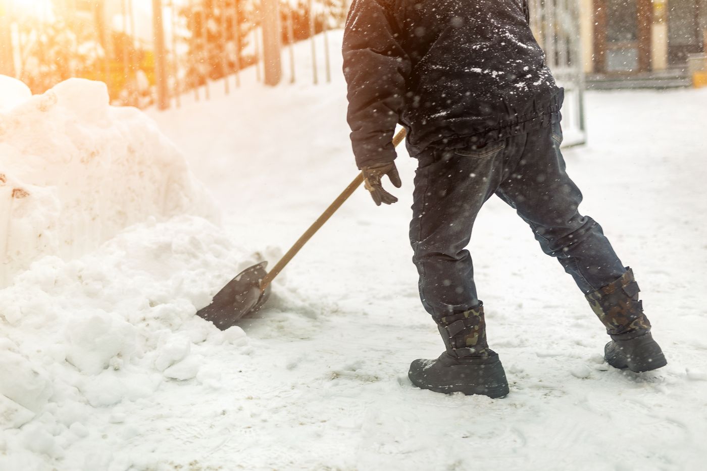 Mitarbeiter räumt nach Schneefall den Gehweg vor einem Haus, Winterdienst im Westerwald